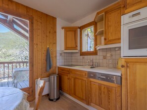 A kitchen with wooden cabinets, a stainless steel sink, and a window with a view of greenery.