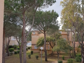 A courtyard with trees, a lamp post, and a building with a beige facade.