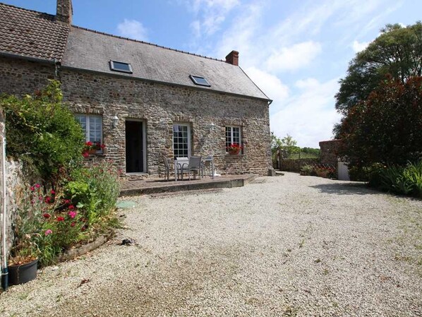 A stone building with a gravel driveway and a patio area with outdoor seating.