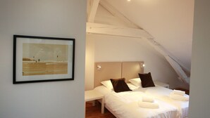 A bedroom with two beds, a framed picture on the wall, and a sloped ceiling. - bloch duplex 165m2 city center 4br3bth (Colmar)