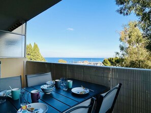 An outdoor dining area with a table set for two, overlooking a coastal view.