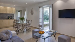 Un espace de vie moderne comprenant un coin repas, une cuisine et un téléviseur fixé au mur.
