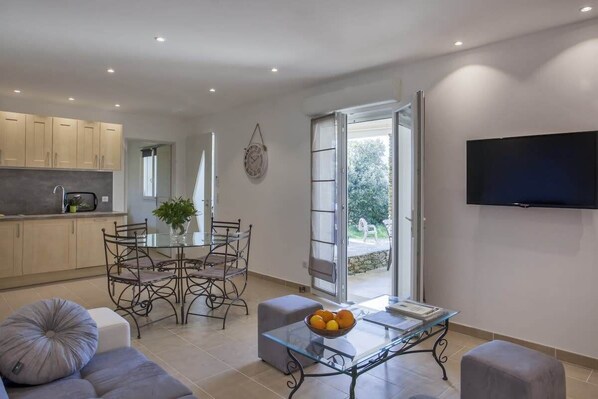A modern living space with a dining area, kitchen, and a TV mounted on the wall.