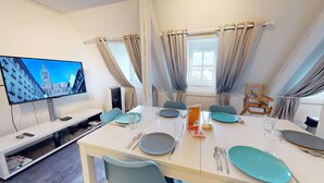Una habitación de hotel moderna con zona de comedor, televisor de pantalla plana y vistas a una catedral.