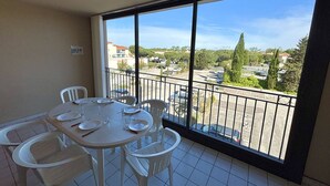 A balcony with a table set for four, overlooking a parking area and buildings.