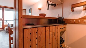 A kitchen with wooden cabinets, a countertop, a coffee machine, and a bowl on the counter. - Arc 1800: 2-Room Apartment, 6 Persons, Pets Allowed, WiFi (Les Arcs 1800)