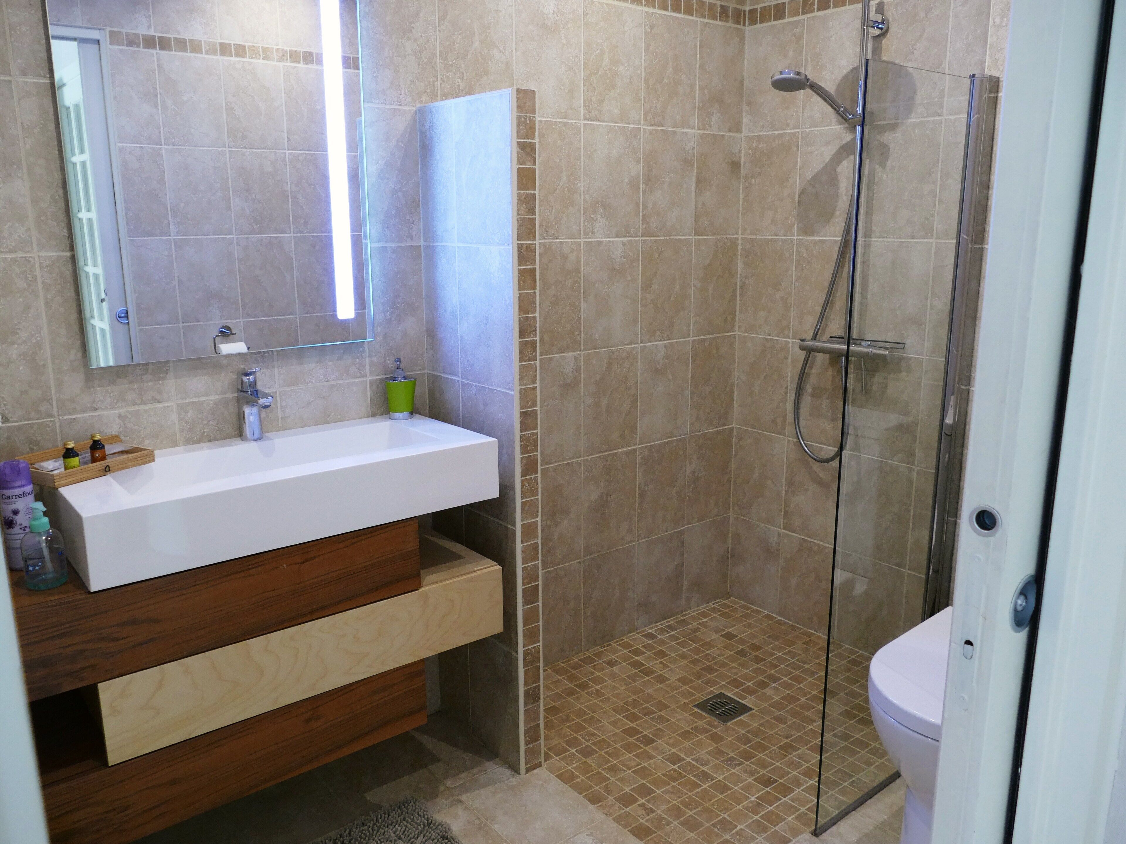Ein Badezimmer mit einem weißen Waschbecken, einem Holz-Badmöbel und einer Duschkabine.