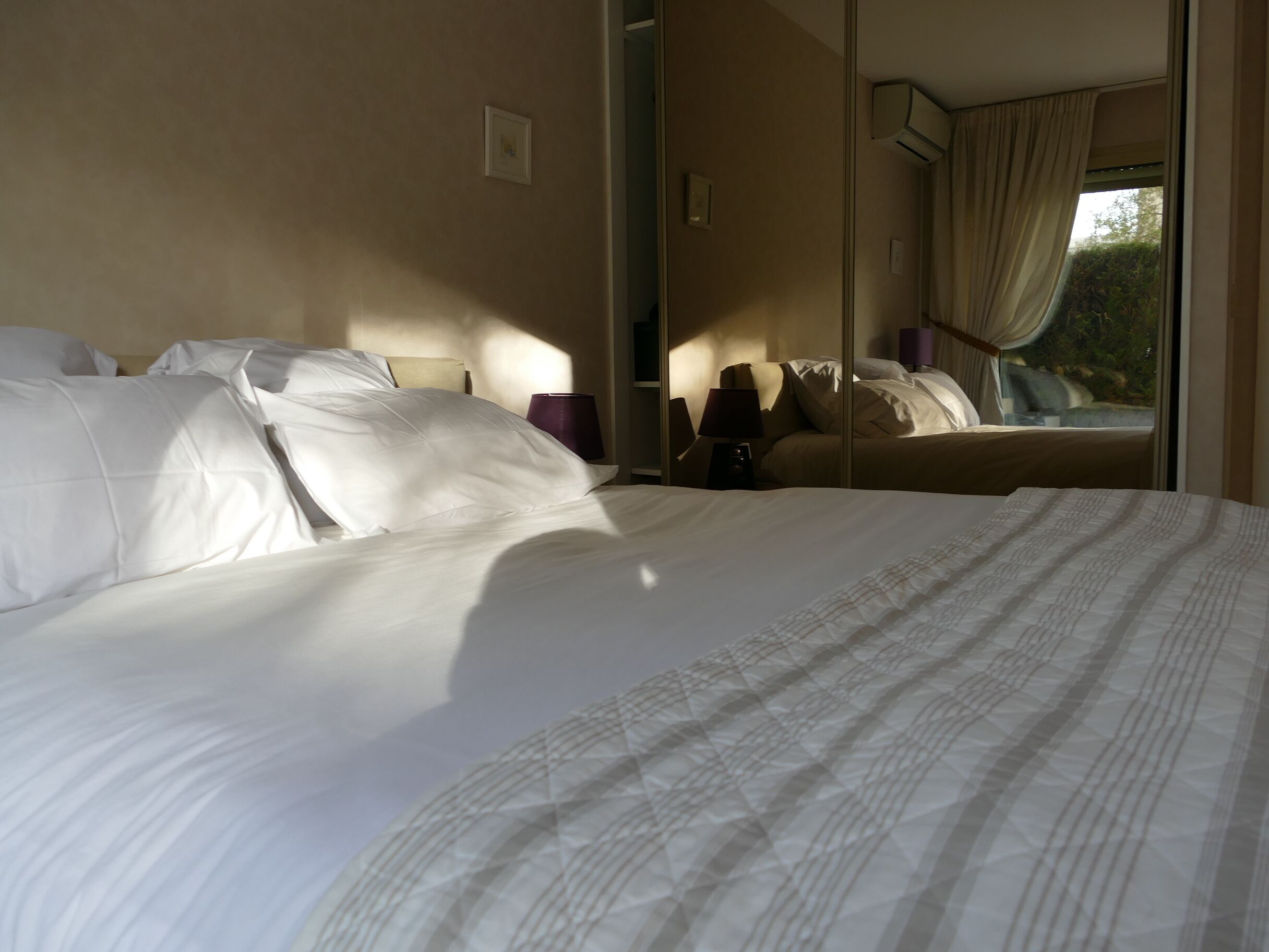 Habitación de hotel con una cama grande, una lámpara de noche y una ventana con cortinas.