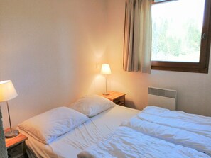 Cozy retreat with a single bed, bedside table, and window with curtains.