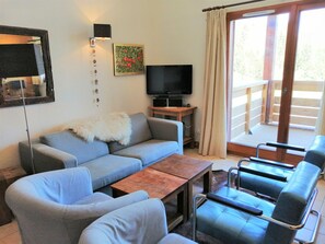 Relax in a cozy living area with a comfortable sofa set, flat-screen TV, and modern chairs.