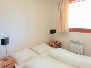 Relax in a serene space with a single bed, bedside table, and window with curtains.