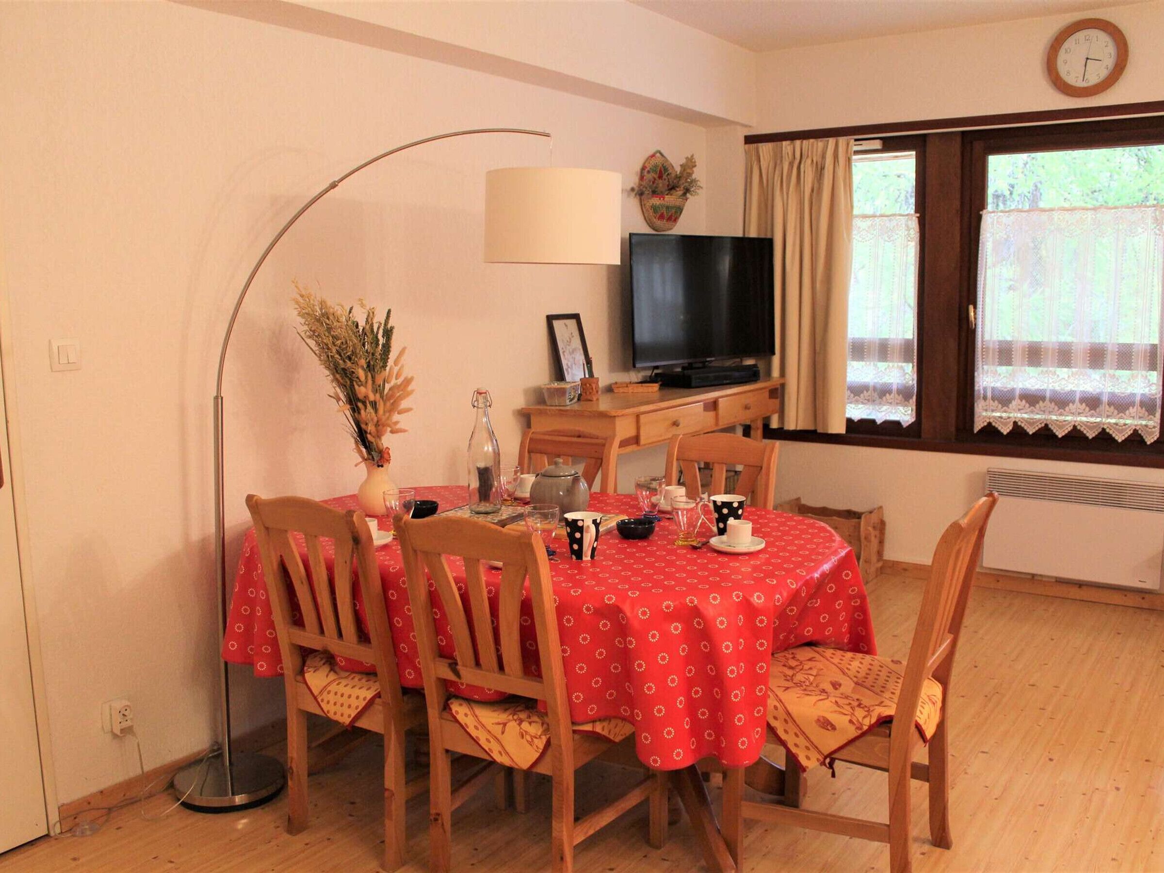 A dining area with a table set for four, a television, and a window with curtains.