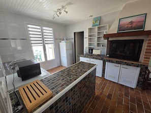 A kitchen with a tiled backsplash, a refrigerator, a coffee maker, and a television.