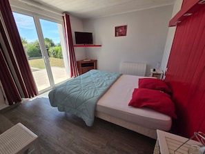 A bedroom with a bed, a TV, and a window with curtains.