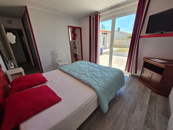 A hotel room with a bed, a chair, a TV, and a view of the outside.