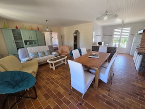 A spacious living area with a dining table, sofas, and a kitchen in the background.