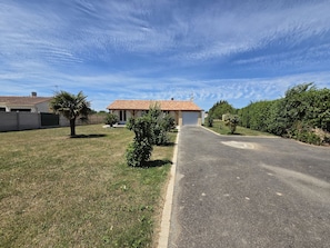 A residential property with a paved driveway, a garage, and a small lawn area.