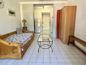 A bedroom with a wooden bed, a glass table, a wardrobe, and a bathroom visible through an open door.