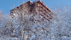 A multi-story building with a modern architectural design, surrounded by snow-covered trees. - Studio for 5, mountain view, balcony, Arc 1800 (Les Arcs 1800)