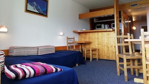 A small, cozy room with two beds, a wooden desk, and a chair. There is a microwave and a kettle on the desk. - Studio for 5, mountain view, balcony, Arc 1800 (Les Arcs 1800)