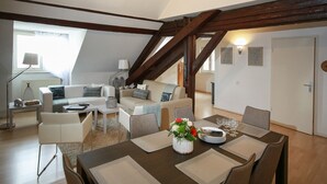 Una sala de estar moderna estilo loft con comedor, que presenta vigas de madera expuestas, un ventanal grande y una acogedora zona de estar.
