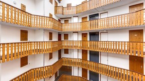 Un atrio de varios niveles con barandales y puertas de madera en cada planta.