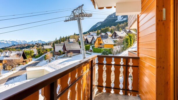 Un balcón de madera con vistas a un pueblo nevado y montañas.
