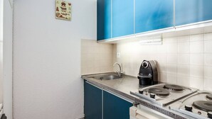 Una cocina compacta con estufa a gas, cafetera y lavamanos.