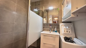 Een kleine badkamer met een douche, wastafel en toilet.