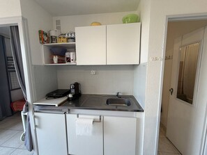 A compact kitchen with a sink, a coffee maker, and a small refrigerator.