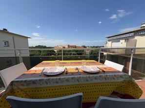 A balcony with a table set for two, overlooking a cityscape. - Cozy Studio Alcove, 300m from Beach, Balcony, Private Parking, Sleeps 3 (Argelès-sur-Mer)
