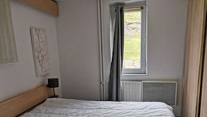 A bedroom with a bed, a window with curtains, a radiator, and a wall-mounted artwork. - Ski-in/Ski-out Apartment for 6 with Balcony, South-Facing, 1 Bedroom, La Mongie (La Mongie)