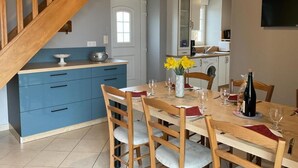 Een eetgedeelte met een houten tafel voor twee personen, blauwe kasten en een keuken op de achtergrond.