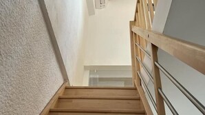 Un escalier en bois avec une rampe en métal, qui monte.