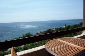 A balcony with a wooden table and a view of the ocean. - YVETTE MINI-VILLA - FACING THE SEA- 3*** (TARCO CONCA)