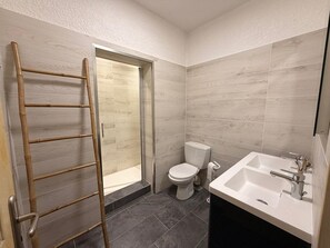 Un baño con inodoro, lavamanos y una escalera apoyada en la pared.