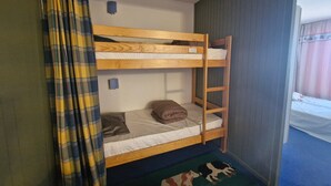 Een slaapkamer met een stapelbed, een geruite gordijn en een vloerkleed met koeienprint.