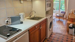 Une cuisine compacte équipée d’un four, d’un micro-ondes et d’un lave-linge intégrés.