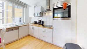 A modern kitchen with white cabinets, a dishwasher, a microwave, a coffee maker, and a built-in oven. - schlumberger 120m2 city center 3br 2bth (Colmar)
