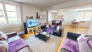 A modern living room with a flat-screen TV, sofas, a coffee table, and a dining area with chairs and a table. - schlumberger 120m2 city center 3br 2bth (Colmar)