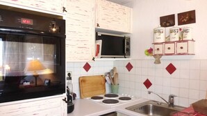 Una cucina con mobili bianchi, un forno a microonde, un piano cottura e un lavello.