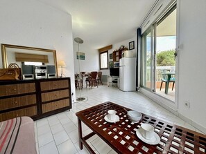 A compact living space with a kitchenette, dining area, and a balcony with a view.