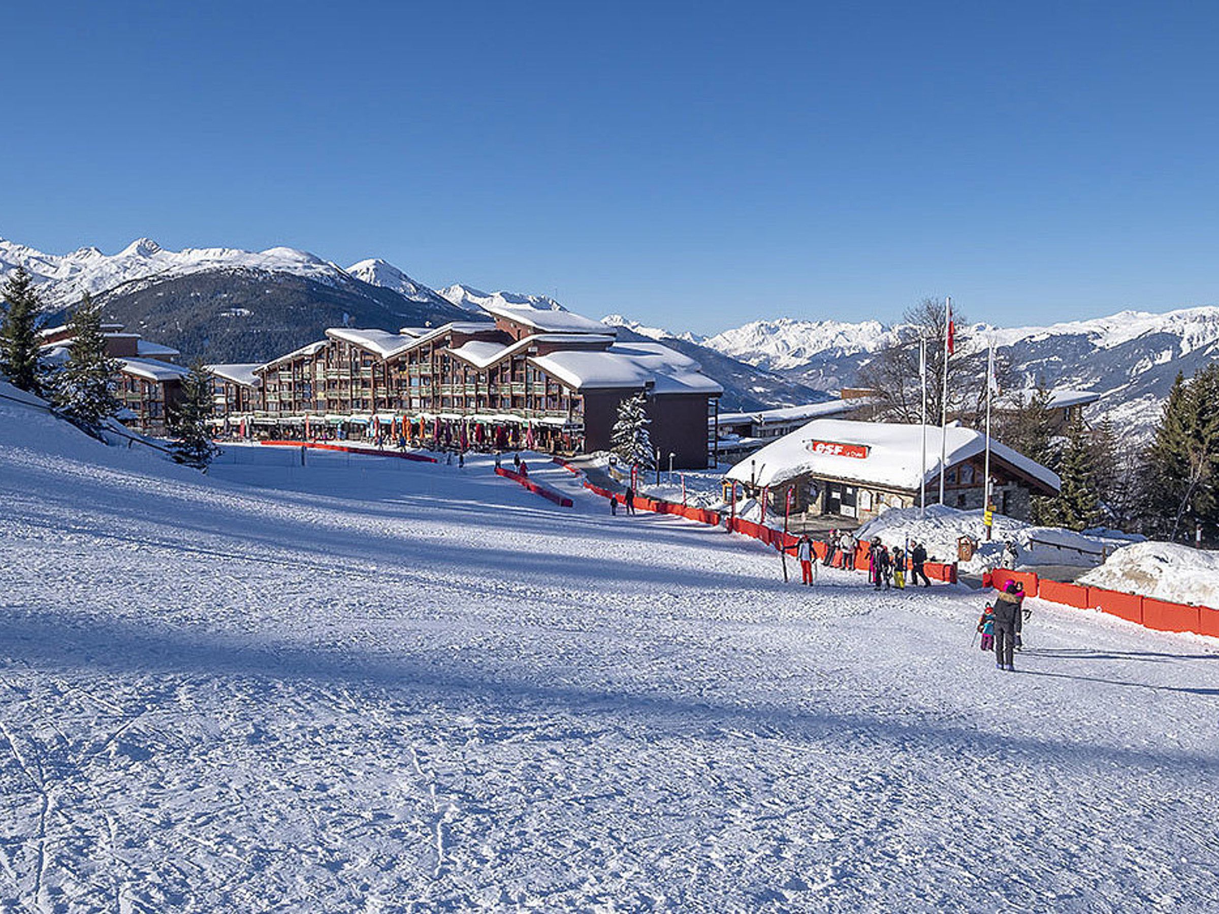 A ski resort with multiple lodges, a ski slope, and a mountain backdrop.