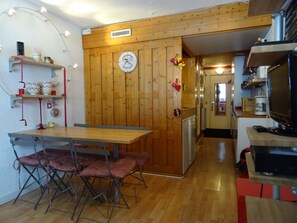 A compact kitchen with a wooden wall, a clock, and a small refrigerator. - Ski-in/ski-out studio for 4 at Charvet, Arc 1800 (Les Arcs 1800)