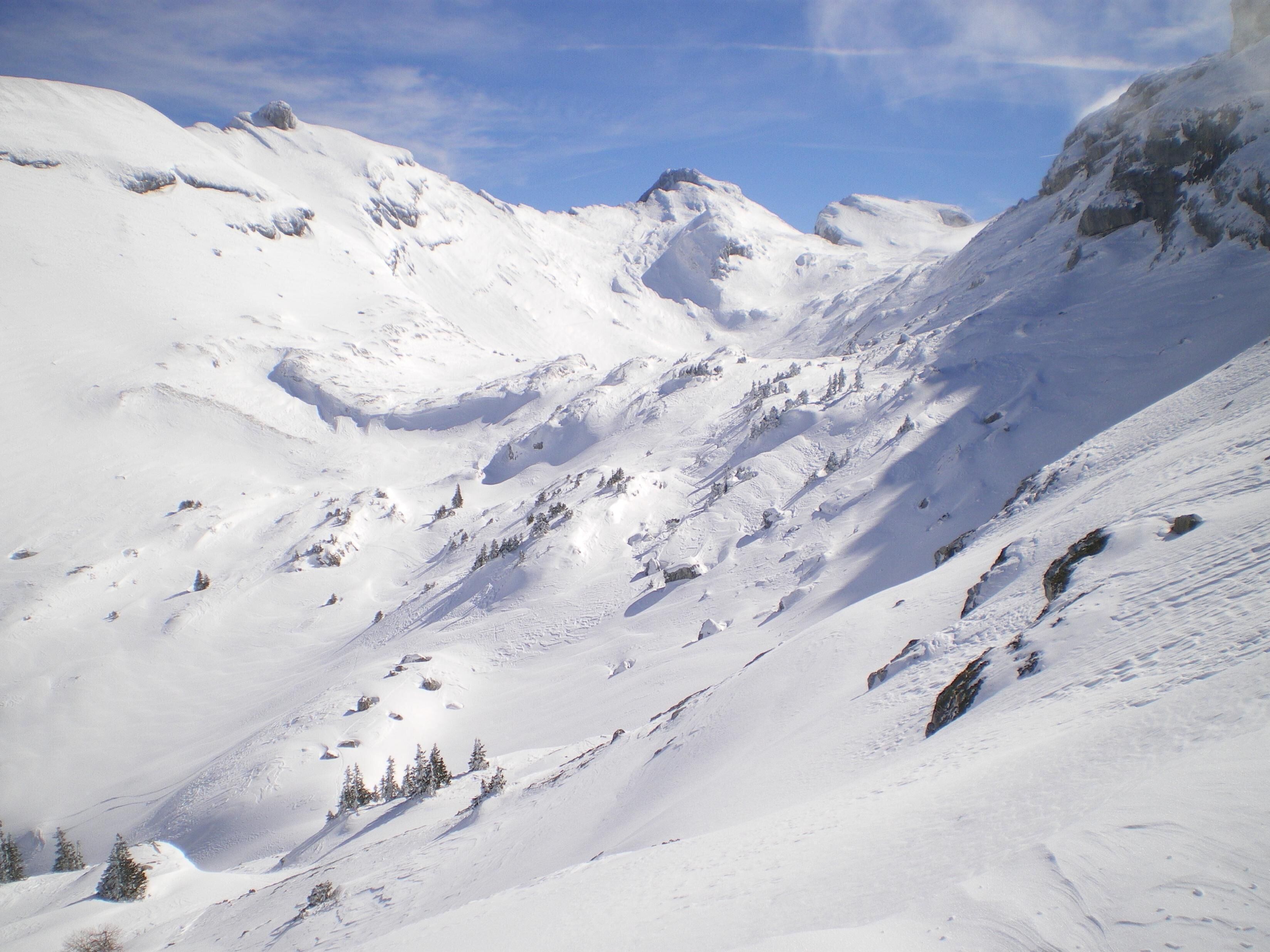 A snow-covered mountain landscape with rocky outcrops and sparse vegetation.