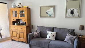 Una sala de estar acogedora con un sofá gris, un aparador de madera y dos cuadros de osos polares en la pared.