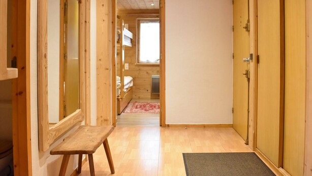 A narrow hallway with wooden walls and a bench, leading to a room with a bed and a window. - Ski-In/Ski-Out Apartment with Fireplace and Balcony in Méribel (Méribel)