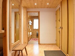Un pasillo estrecho con paredes de madera y un banco, que conduce a una habitación con una cama y una ventana.