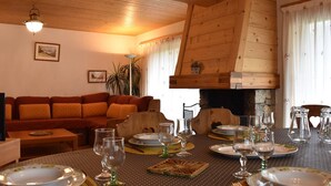A cozy living room with a wooden ceiling, a fireplace, a sofa, and a dining table set for six. - Ski-In/Ski-Out Apartment with Fireplace and Balcony in Méribel (Méribel)