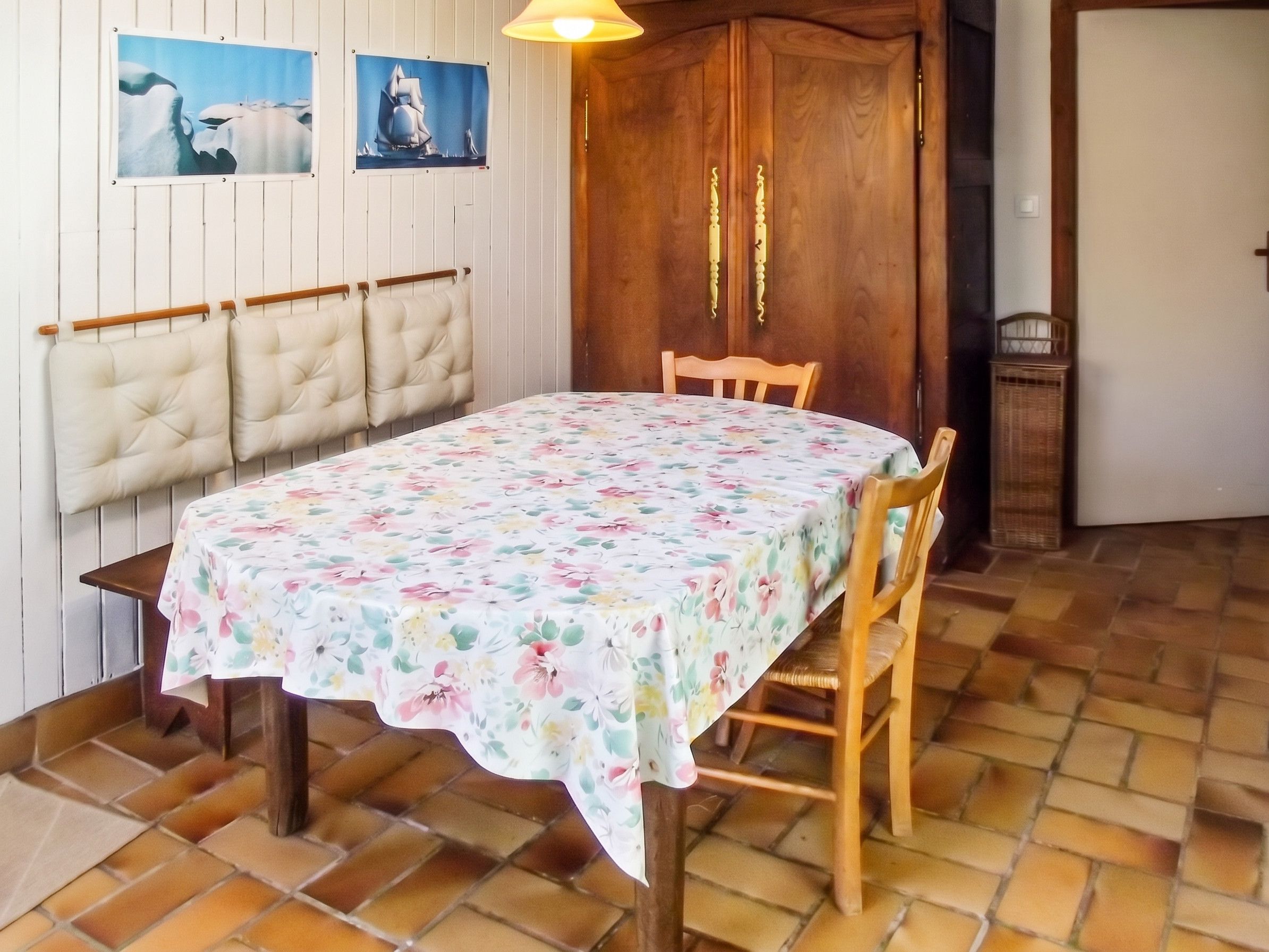 Zona de menjador amb una taula preparada per a dues persones, un armari de fusta i un sòl d'rajola.
